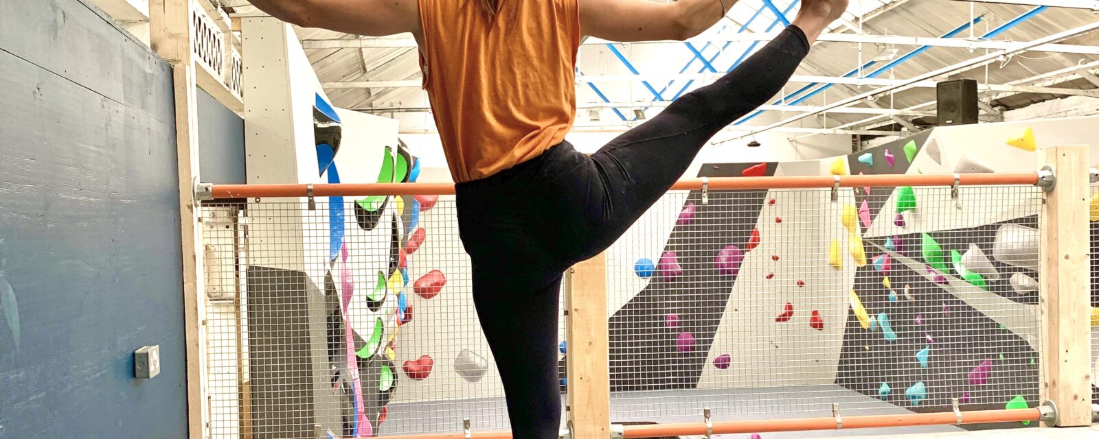 yoga posture in front of climbing wall