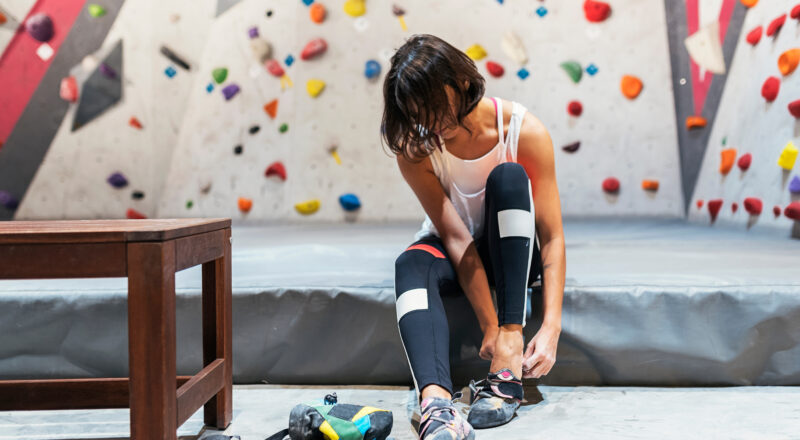 woman putting on climbing shoes